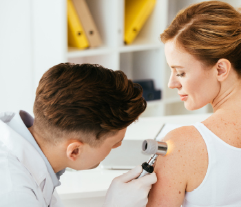 Dermatolog pregleduje kožne spremembe pri pacientki