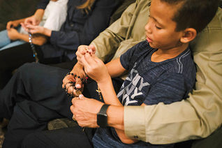 A young boy prayer with rosaries.