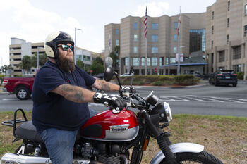 Brett Davison, testicular cancer survivor, on his motorcycle in front of Moffitt Cancer Center.