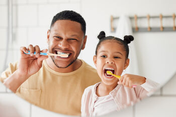 Dad and daughter brushing teeth in the bathroom