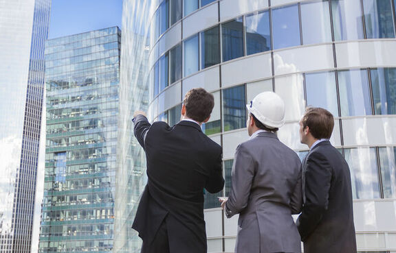 Two businessmen and an architect looking up at office building