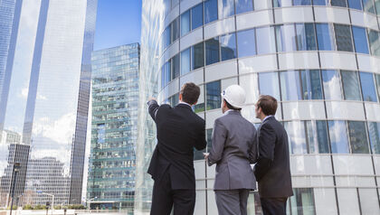Two businessmen and an architect looking up at office building