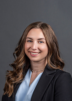 Headshot of Cara Peccerillo, who smiles while wearing a baby blue blouse and black blazer