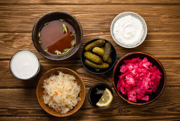 bowls full of assorted fermented foods like sauerkraut, Greek yogurt, pickles, etc.