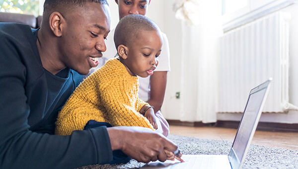 couple on the floor with their baby playing on a laptop