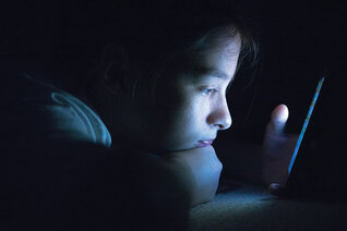 A young child staring closely at a smartphone