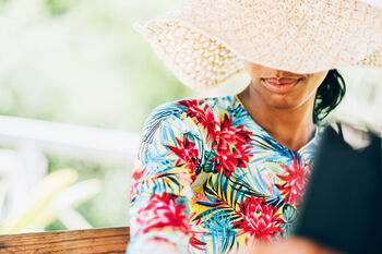 woman outside wearing a wide-brimmed hat and colorful long-sleeve shirt