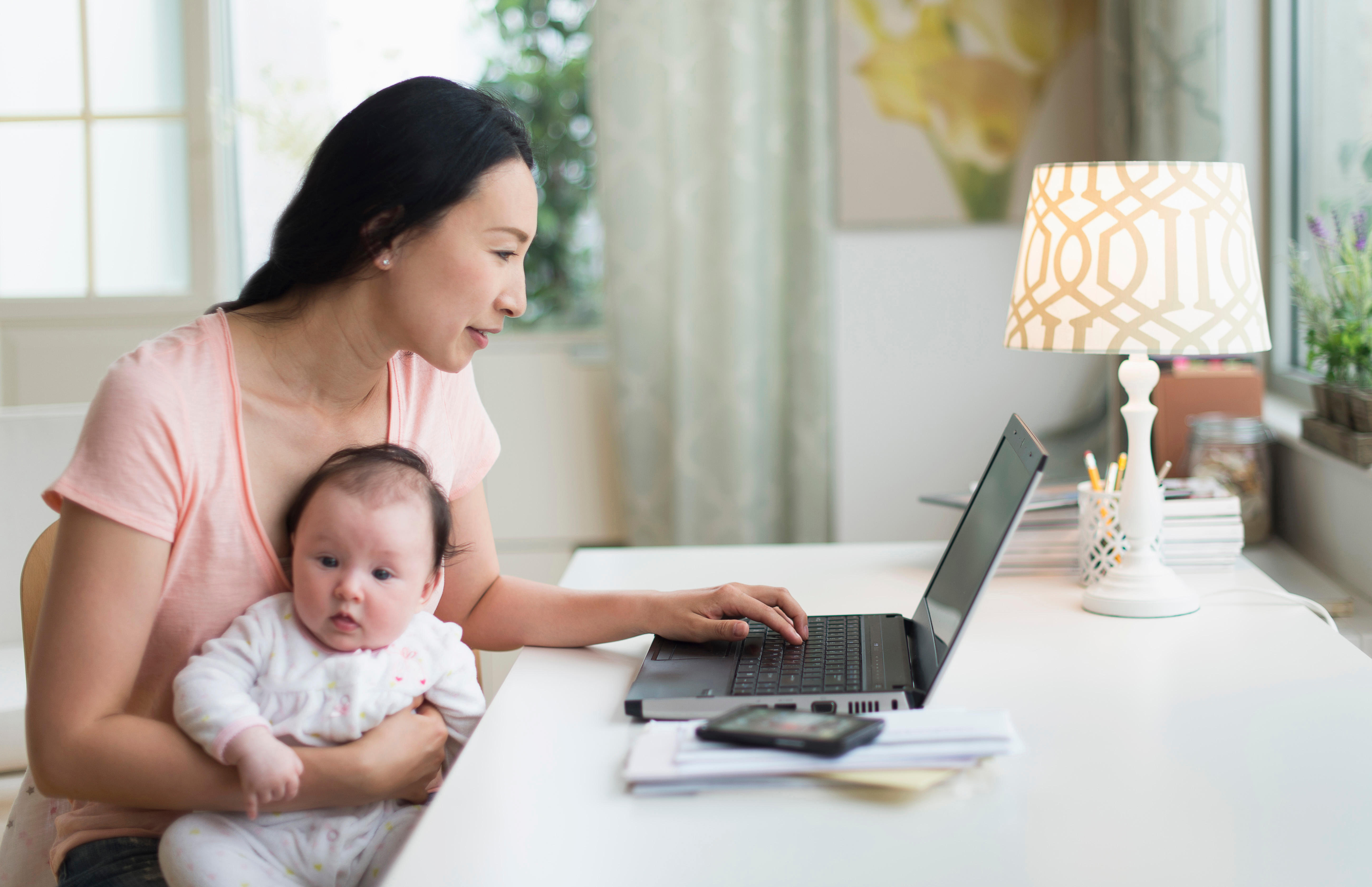 Woman holding baby viewing the healthdirect website