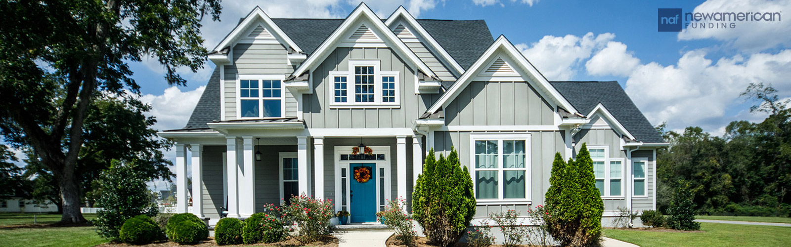 A lovely two-story house with gray vinyl siding surrounded by a well manicured lawn