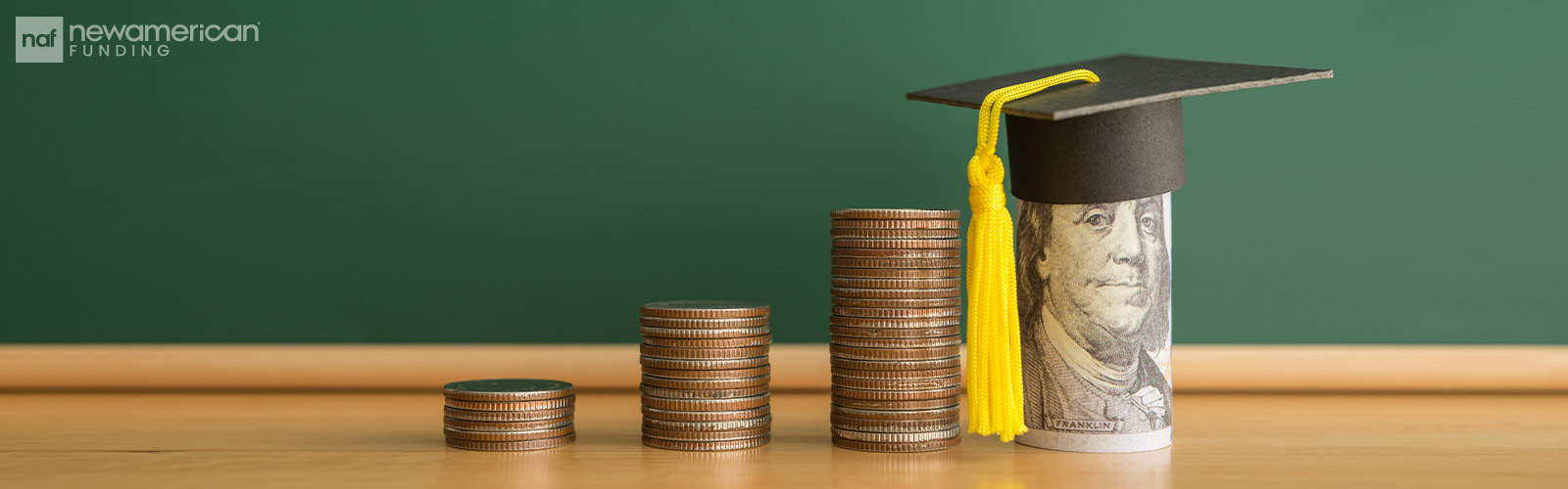 stacks of coins and a roll of cash with a graduation cap on top