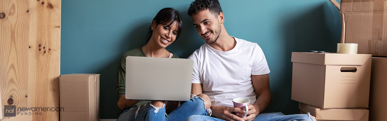 couple sitting with a laptop on the floor of their new home