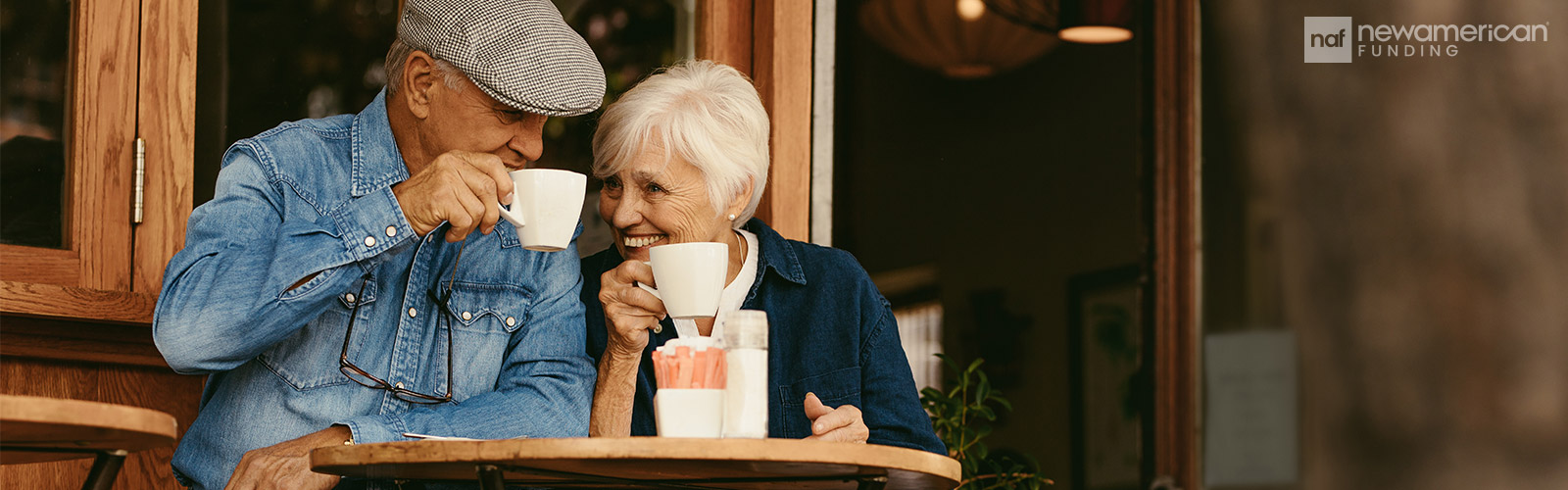 happy senior couple sitting outside a cafe and drinking coffee