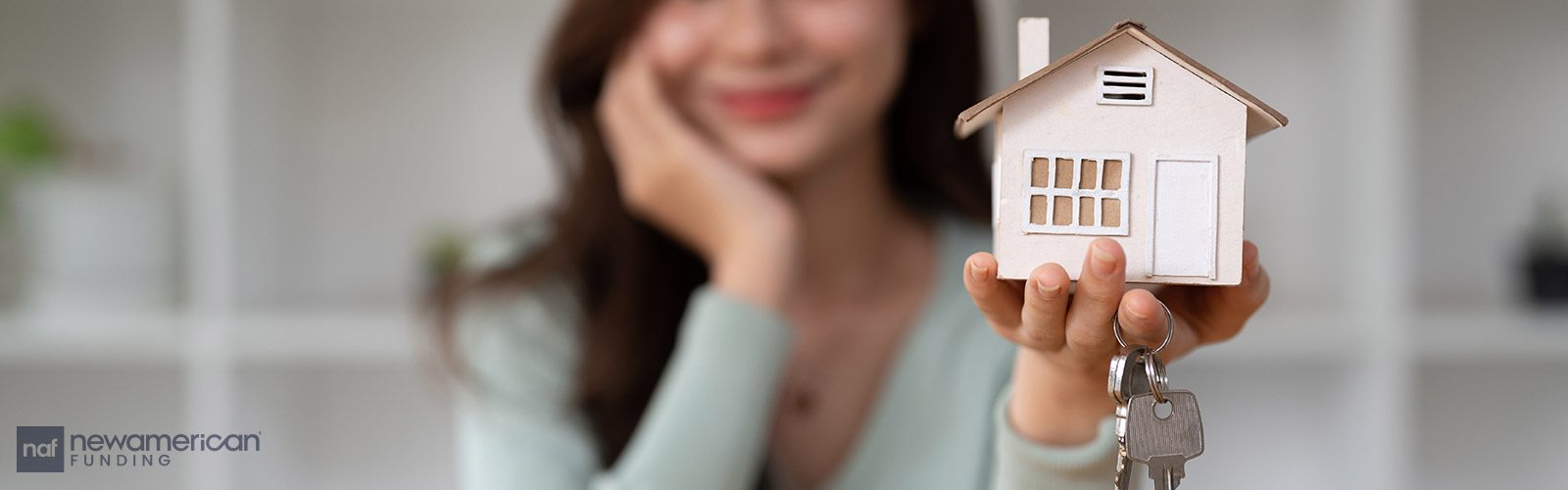 woman holding a house model and house keys