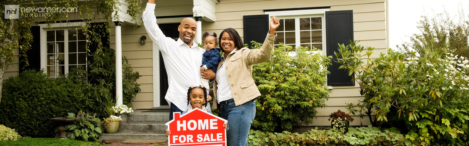 black family standing with a sold sign in front of their new home