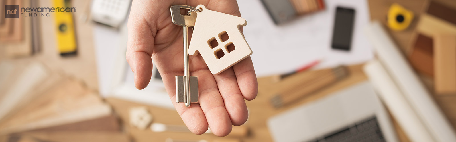 A hand holding a key ring with a key and a small model of a house