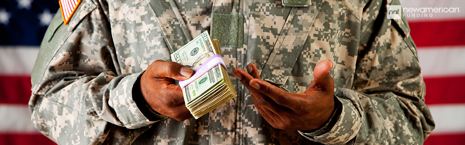 A Black man in a American military uniform holds a stack of 50 dollar bills