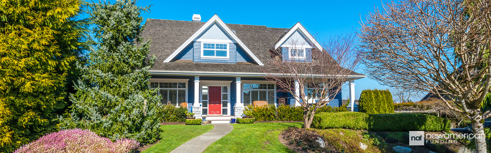 A blue two-story, vinyl-sided house sits on a well manicured lawn