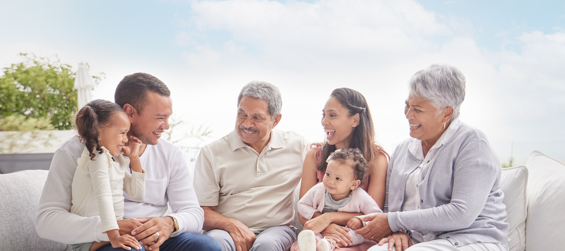 A multi-generational family sitting outside on a couch.