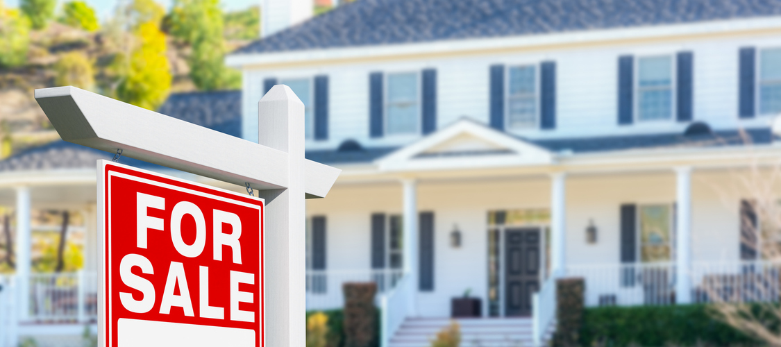 A white, suburban, Colonial house with a red 'For Sale' sign planted in front.