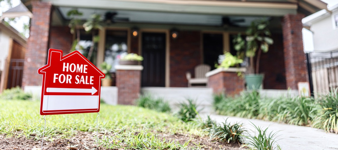 A cute Craftsman house with a 'For Sale' sign in front of it.