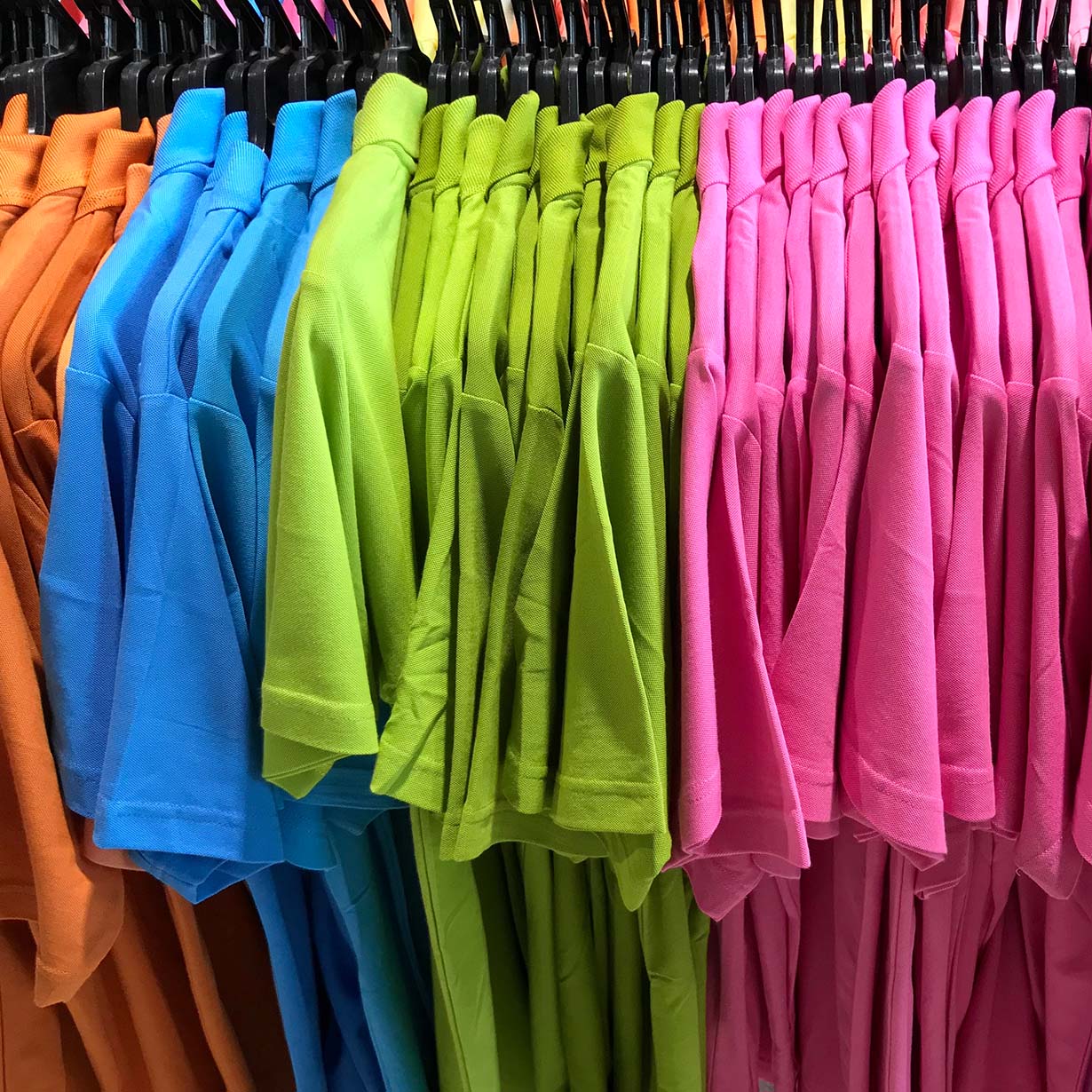 Clothes rack with several t-shirts, organised by colour