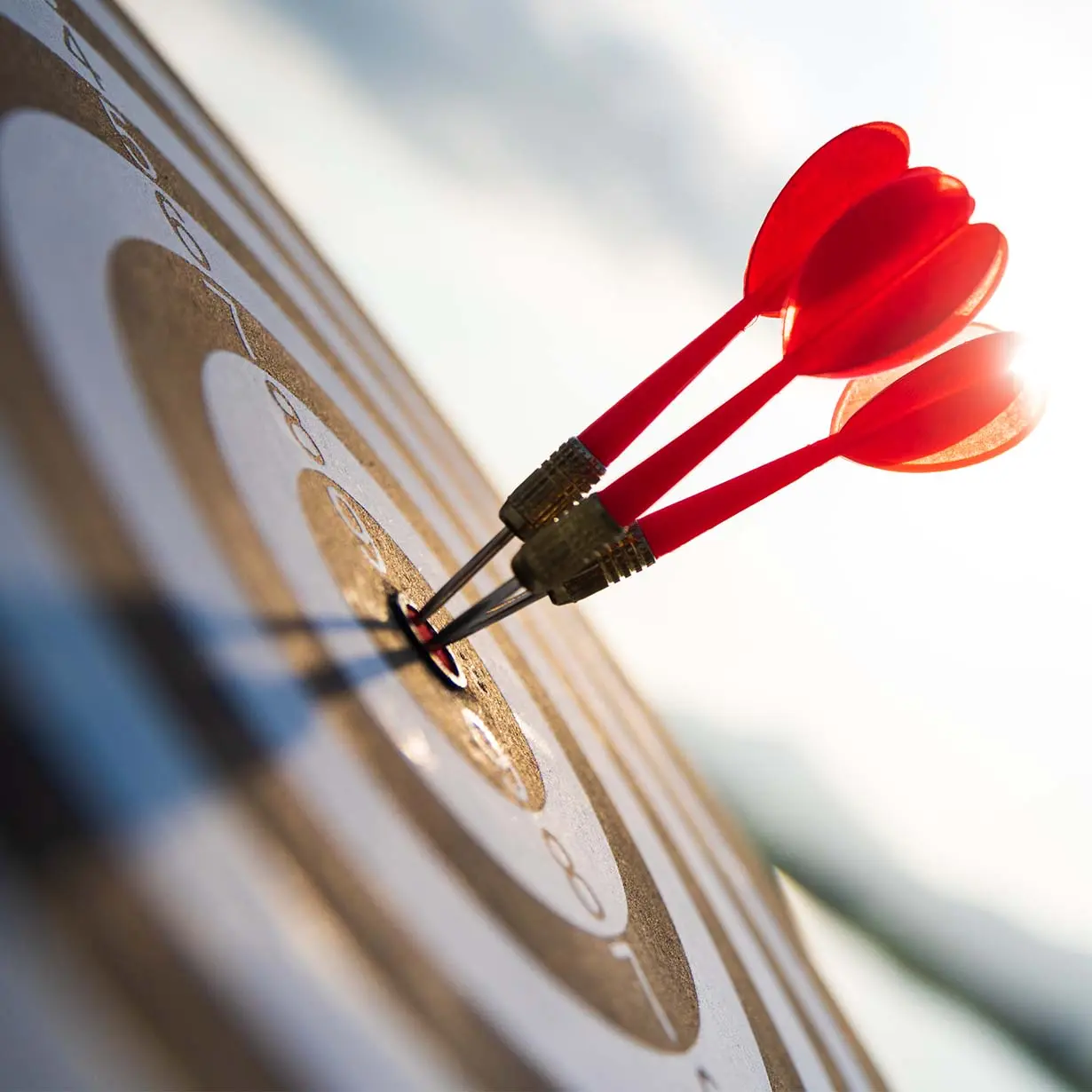 Three red darts perfectly hitting the bullseye on a dartboard