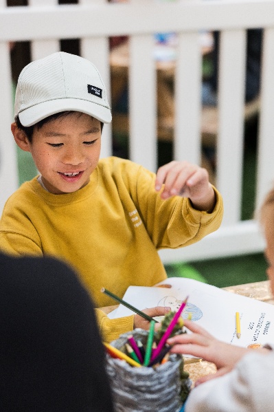 Boy at table selecting coloured pencils