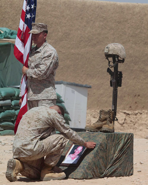 A kneeling Marine pays his last respects to Marine Lance Cpl. Robert Greniger, killed in combat July 12, 2011, during a memorial service at Patrol Base Wishtan in Afghanistan on July 18. Cpl. Anthony Marquez, a close friend of Greniger, stands at attention with the U.S. flag. (Photo courtesy of Anthony Marquez)