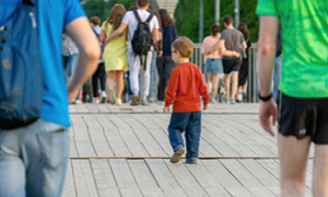 Izgubljen otrok v množici - deček v rdeči majici sam hodi med množico odraslih