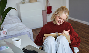 Študentka sedi v spalnici in v zvezek zapisuje svoje SMART cilje, vezane na življenjski projekt.