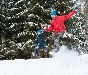 Oče z otrokom uživa na snegu, po tem, ko sta prej uživala v zimskih športih.