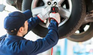 Mehanik v vulkanizerski delavnici zaključuje premontažo gum na vozilu.