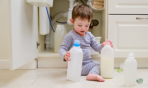 Malček se igra v kopalnici s čistili, ki jih je našel v omari - simbolna slika za zaščito otrok doma