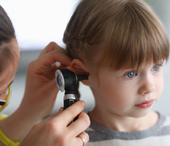 Zdravnica išče znake vnetja ušesa pri otroku