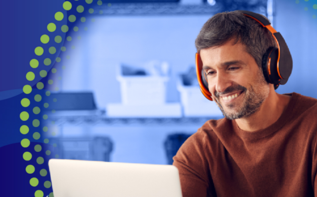 Man at laptop with headphones on smiling.