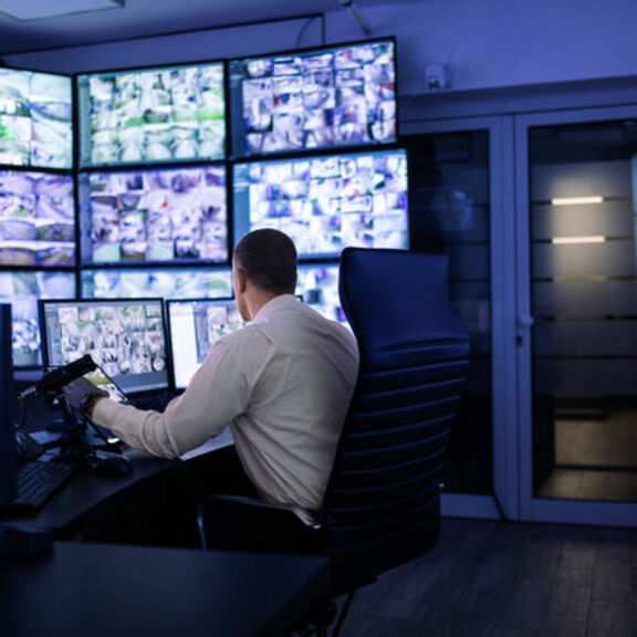 Man working in surveillance room looking at monitors
