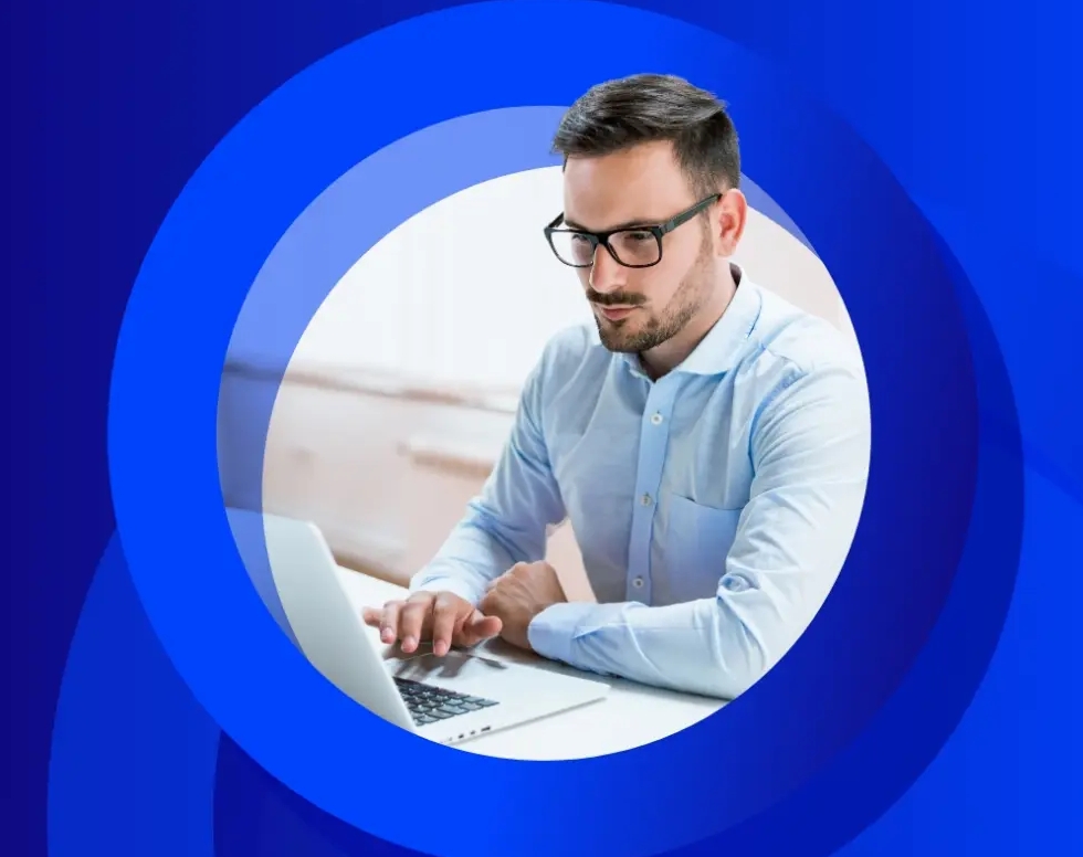 A man with glasses and a light blue shirt works on a laptop, framed by concentric blue circles.
