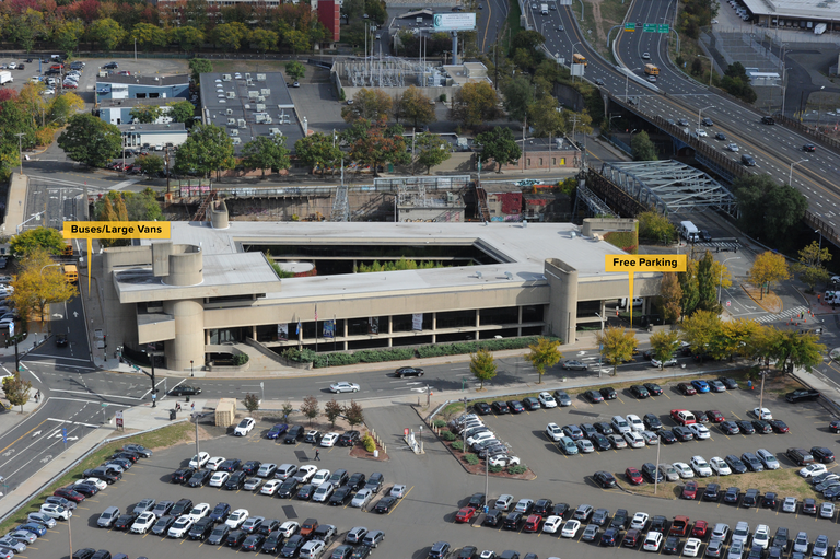 Aerial photo of the McGivney Pilgrimage Center enhanced to indicate in English the bus and van parking along with the free parking beneath the building. 