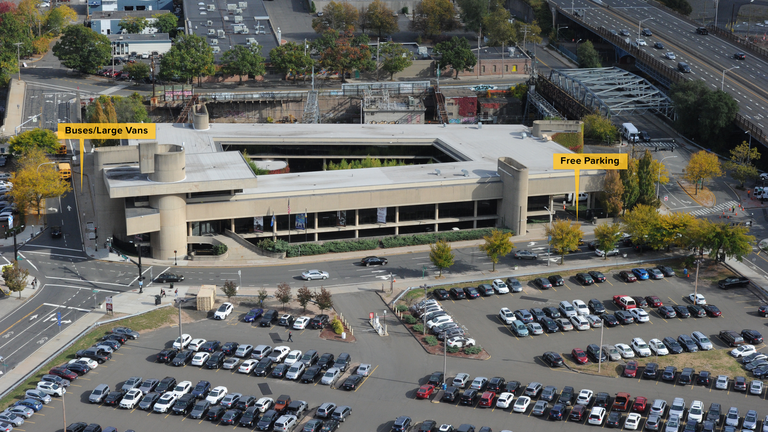 Aerial photo of the McGivney Pilgrimage Center enhanced to indicate in English the bus and van parking along with the free parking beneath the building. 