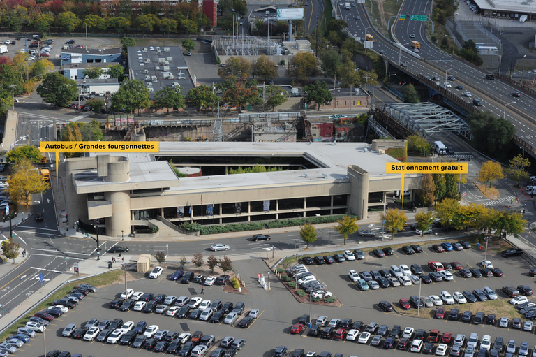 Aerial photo of the McGivney Pilgrimage Center enhanced to indicate in French the bus and van parking along with the free parking beneath the building. 