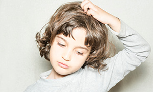 Deček se praska po glavi zaradi naglavnih uši