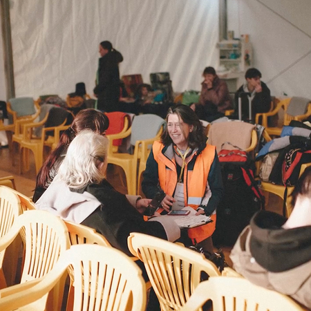 A group of Ukrainian women talk with a volunteer in a refugee camp during war times.
