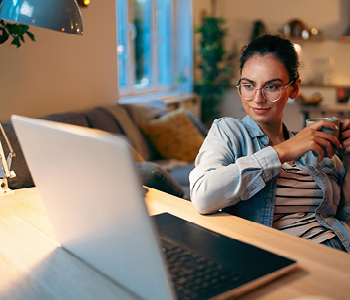Mlada ženska sedi za računalnikom in načrtuje korak za grajenje svoje osebne blagovne znamke.