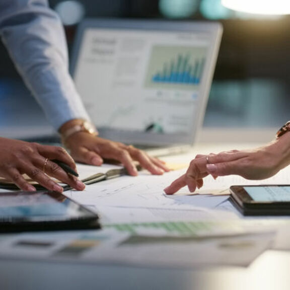 Businesspeople reviewing data on graphs and laptops