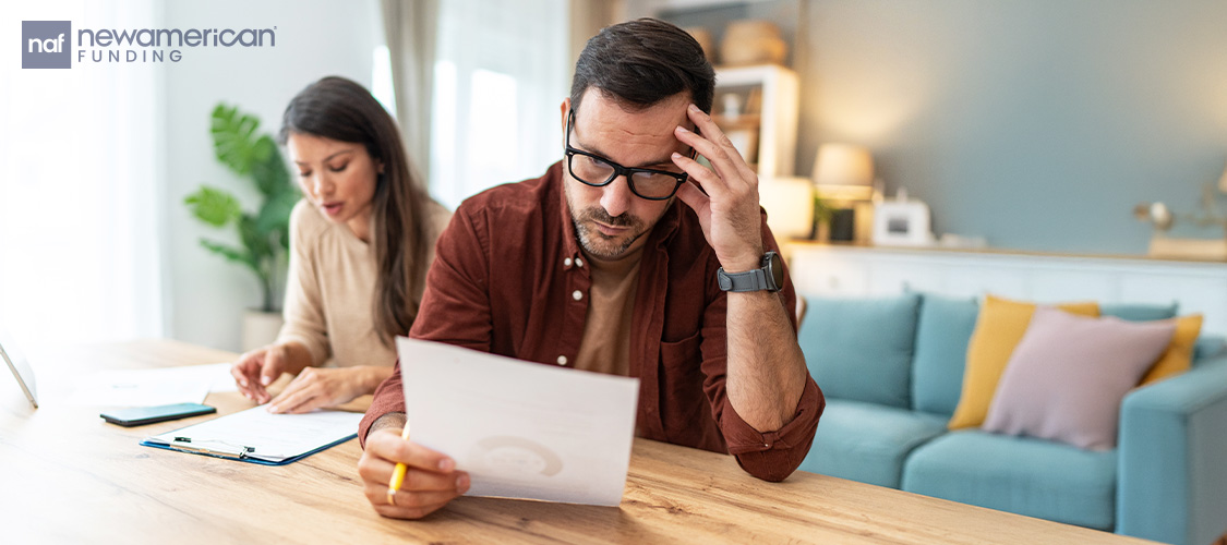 A man looking at paperwork with a woman sitting next to him in a home.
