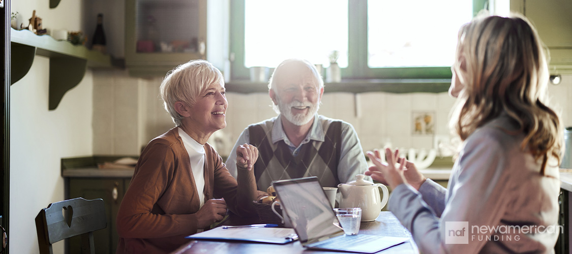 An elderly couple meeting with a loan officer in their home.