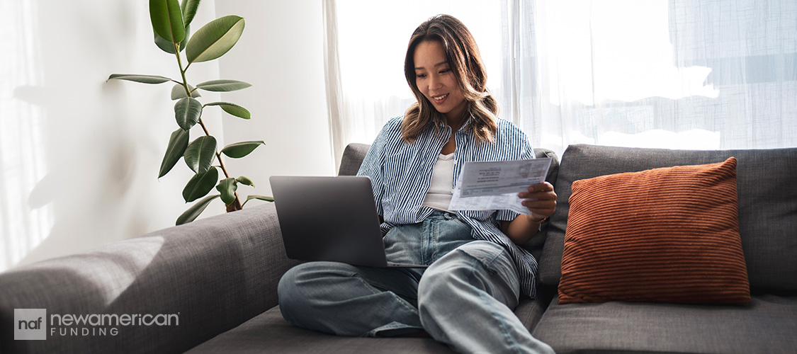 A woman sitting on a couch with a laptop on her lap.