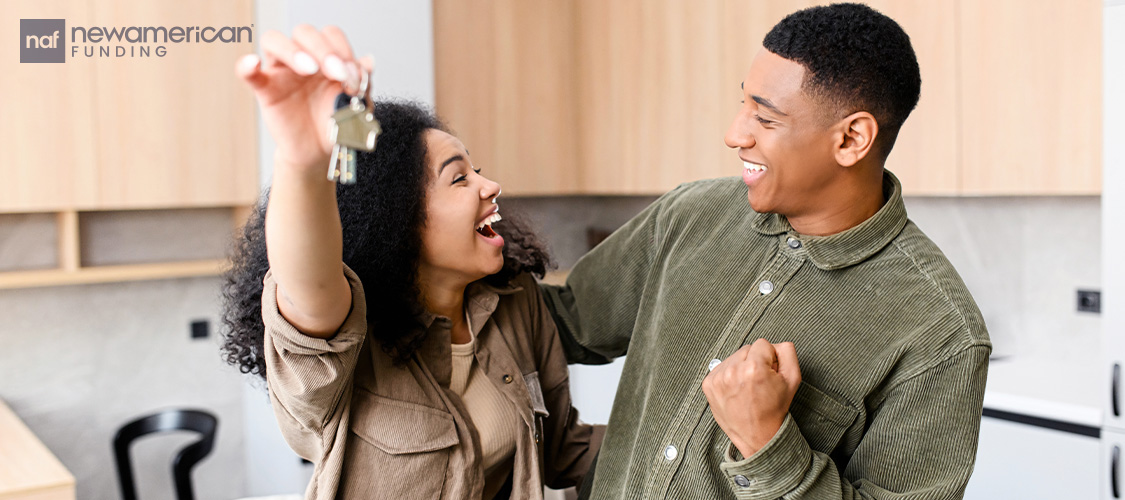A couple celebrating as they hold up keys.