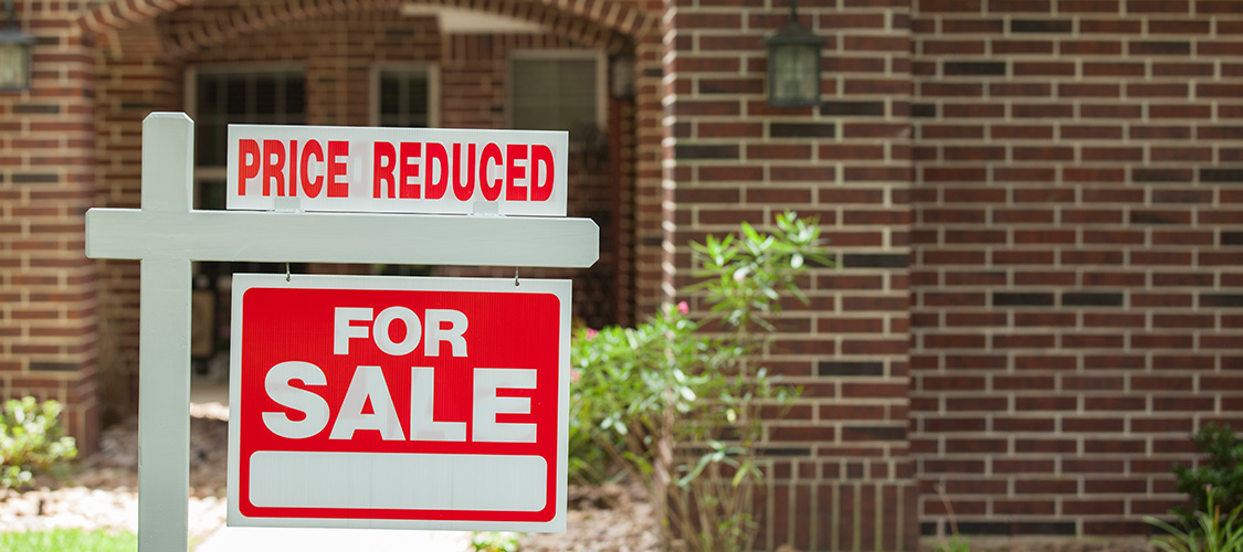 A for sale sign with price reduced on it