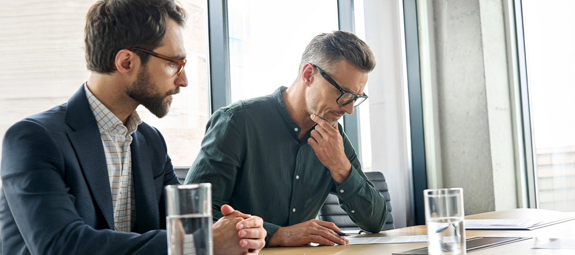 Two men sitting a table discussing a contract